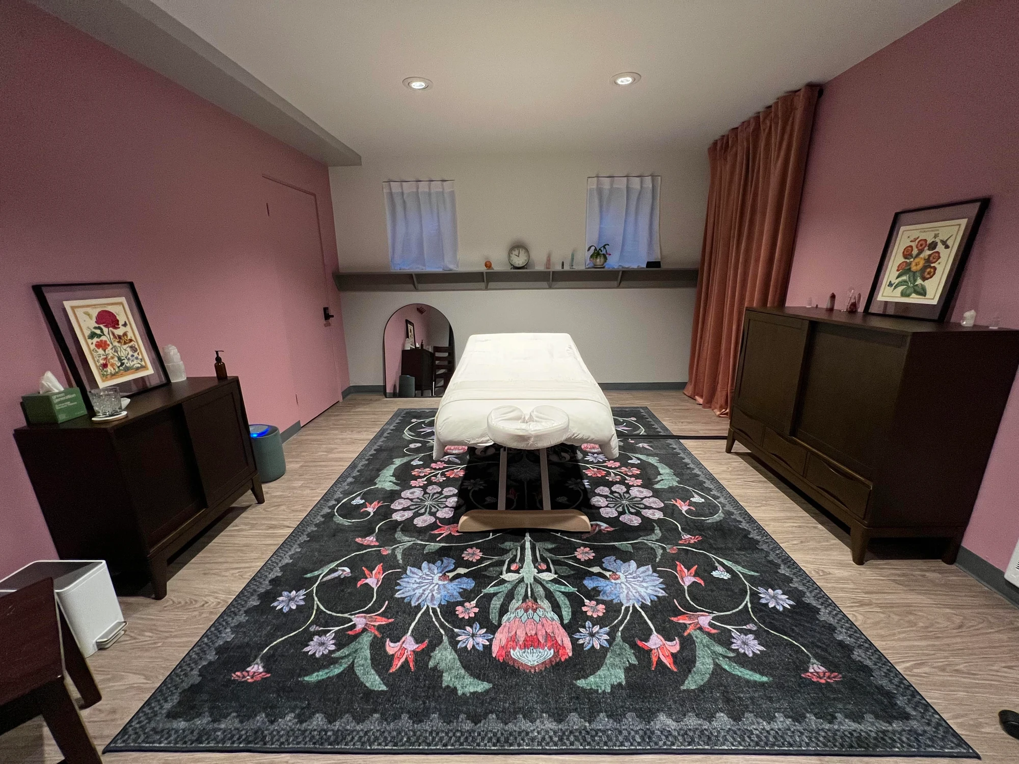 Healing Rose’s massage studio with rose-colored walls, a floral rug and a prepared massage table